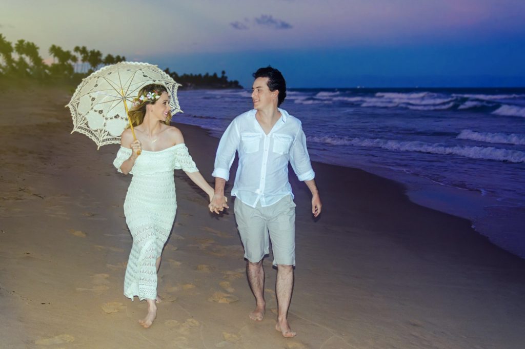 Casal de mãos dadas andando na praia ao anoitecer